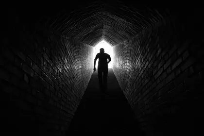 Illustration of a person walking toward light in a tunnel