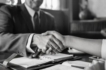 Two professionals shaking hands over a desk